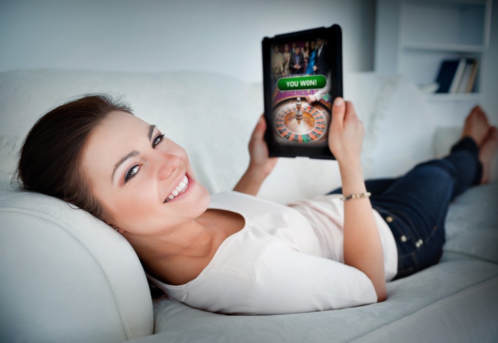 woman relaxing on a couch and playing online games on her tablet